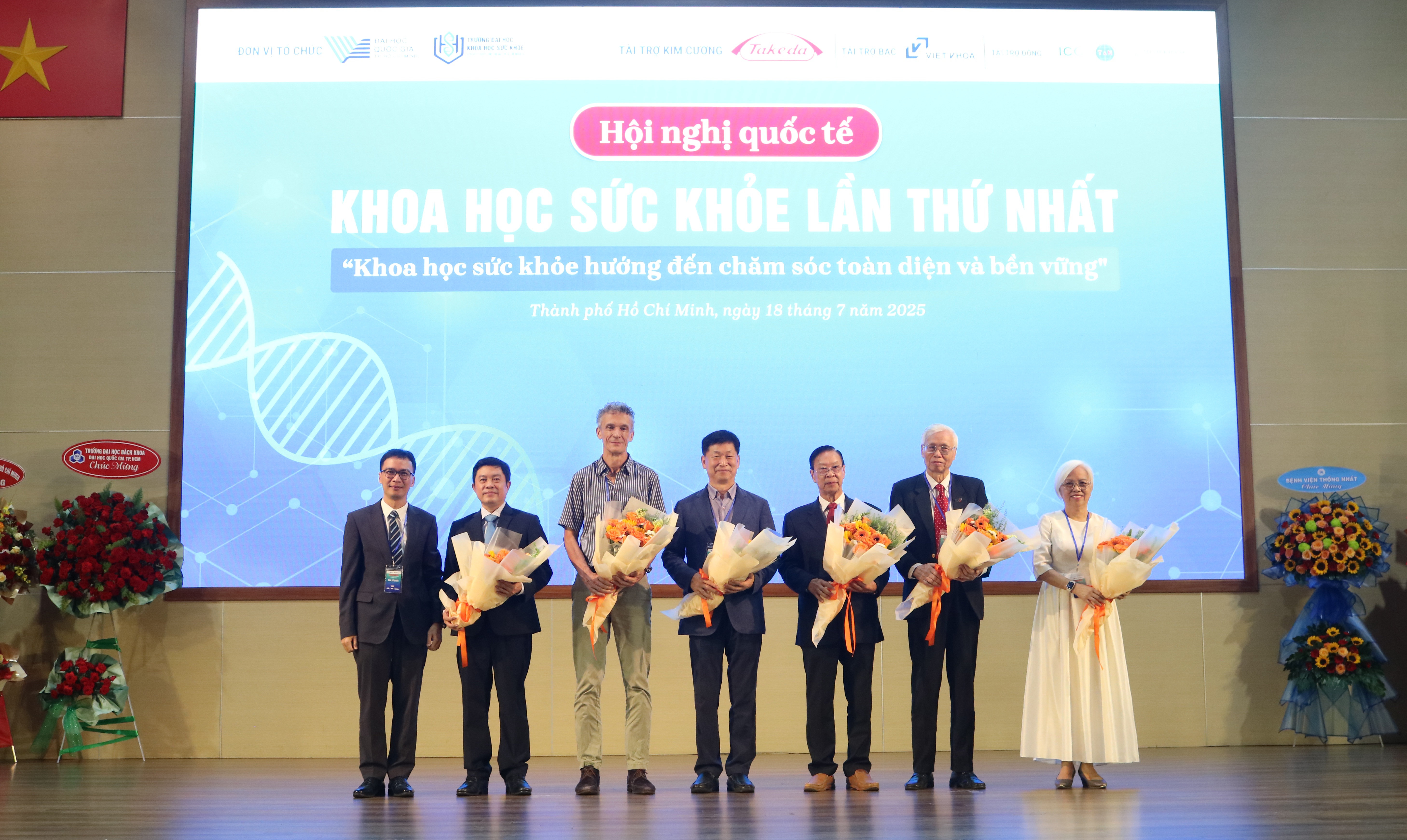 GS.TS Phan Bách Thắng - Hiệu trưởng Trường ĐH Khoa học Sức khỏe (ngoài cùng, bên trái) tặng hoa cho 6 chuyên gia hàng đầu đến từ Anh, Hàn Quốc và Việt Nam tham gia hội nghị.
